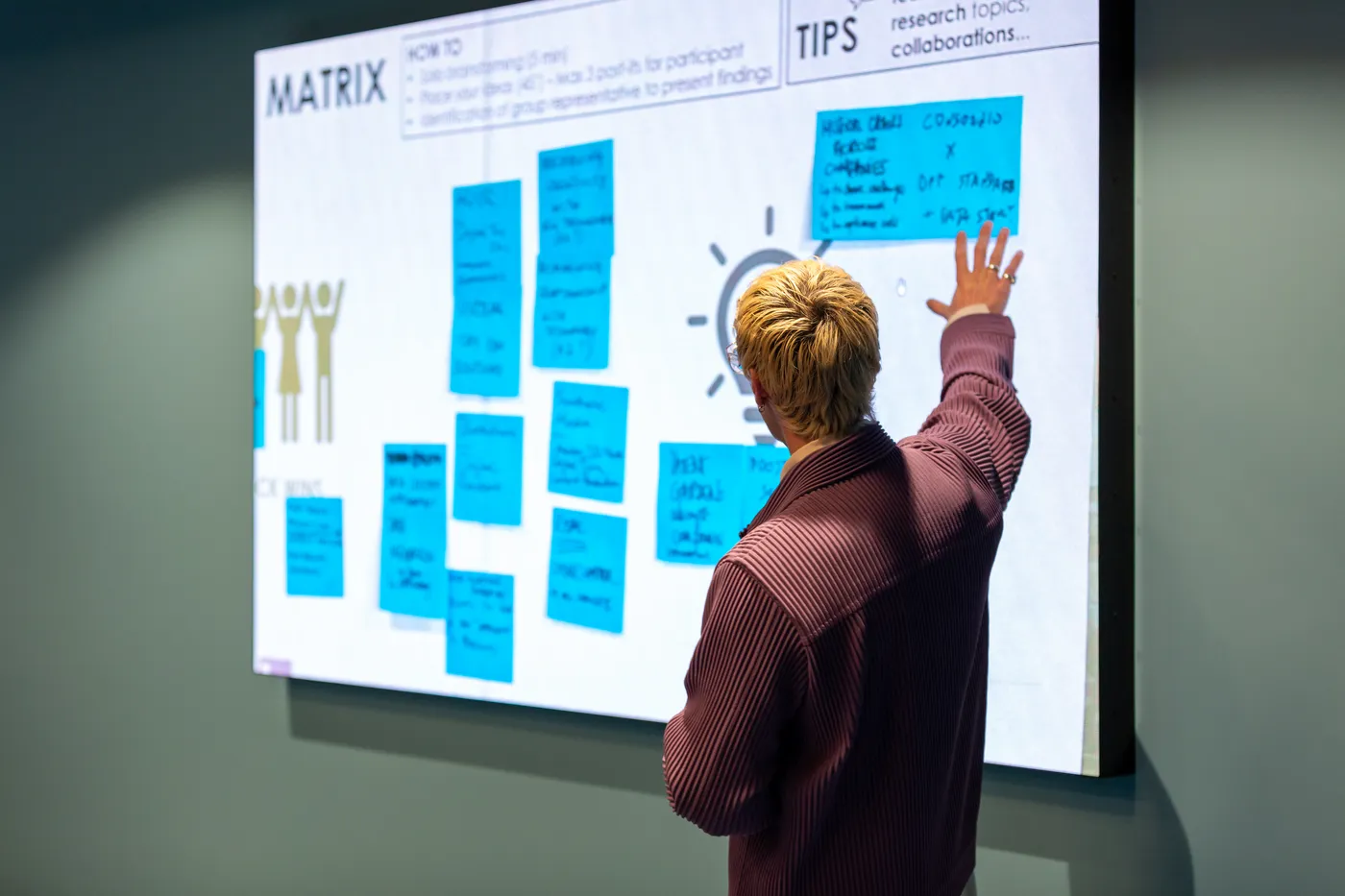 A workshop participant mapping challenges on a board of sticky notes